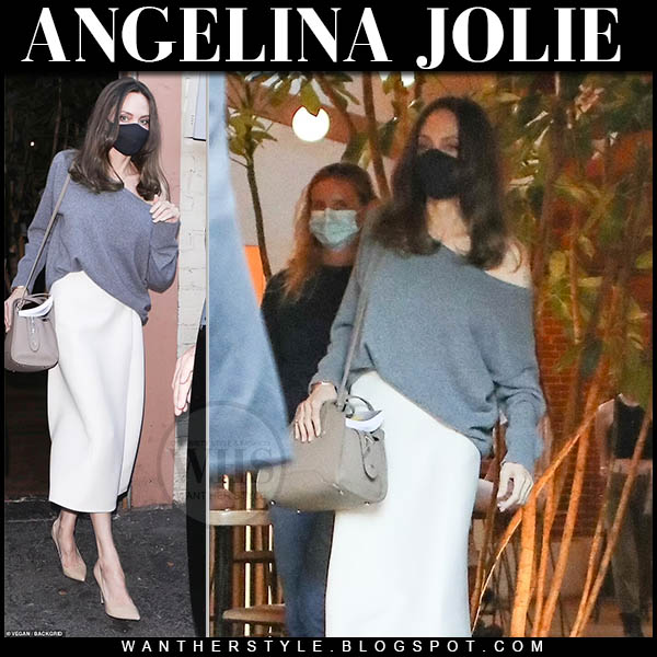 Angelina Jolie in grey one shoulder sweater, white skirt and beige bag