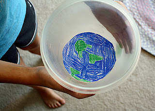 Tessa created a mock Earth orbit with a drawing of the Earth taped into the bottom of a plastic bowl and a marble "moon" (the "moon" is the green blur on the right-hand side). She moved the bowl in a circular motion to experiment with centripetal and centrifugal force.