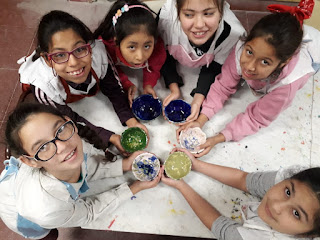 La imagen esta tomada desde arriba y se observa a seis alumnas con una vasija de cerámica de color