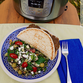 pic of an Instant Pot on a table with a plate of Greek Wild Rice Salad and a falafel-stuffed pita