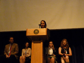 Photo of our Head SLP Elizabeth speaking at the podium while Hugh, Christina, Keebler and I are sitting in the background.