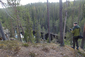 Henkilö katsomassa maisemia korkean töyrään päältä alas jokilaaksoon ja metsään