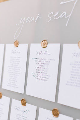 grey seating chart with white papers and gold wax seals