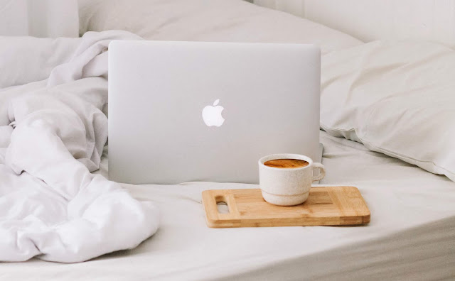 Macbook and coffee on a bed