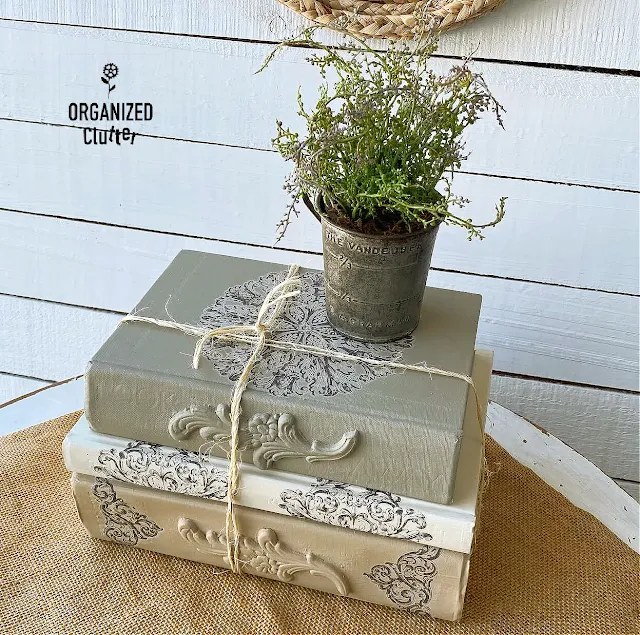 Photo of a DIY decorative book stack with wooden appliques, rub on transfers and Dixie Belle Chalk Paint.