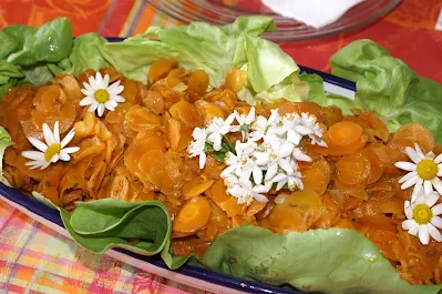 Dies Bild zeigt ein gesundes Gemüsegericht. Das Gericht besteht aus Karotten, Salatblättern und Blumenkohl. Karotten sind eine gute Quelle für Beta-Carotin, Vitamin A und Kalium. Der Teller ist aus Holz und hat einen Durchmesser von etwa 20 cm. Das Gemüse ist auf dem Teller gleichmäßig verteilt. Das Bild wurde in einem hellen Raum aufgenommen. Das Licht kommt von einer Fensterfront, die sich hinter dem Teller befindet. Das Gemüse sieht appetitlich und sehr lecker aus.