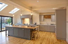 bespoke open plan kitchen diner with bifold doors, Carrara marble and solid oak worktops, farrow and ball Manor House grey and downpipe units, island, integrated appliances, pendant lighting and statement extractor hob. shaker style kitchen inspiration.