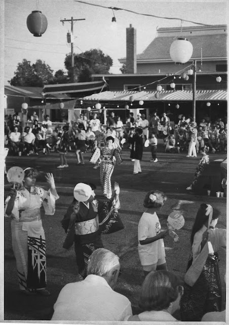 black and white photo of people doing traditional Japanese Obon Dancing in a temple parking lot