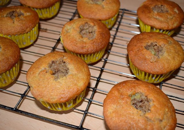 A wire cake rack showing cooked cupcakes with the centres taken out.