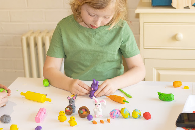 A 6 year old finishing a purple Plasticine rabbit