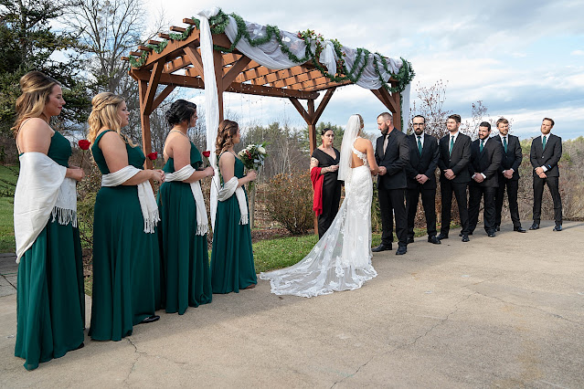 Bride and Groom at the alter wth entire wedding party with Bridesmaids holding red roses Magnolia Farm Asheville Wedding Photography captured by Houghton Photography