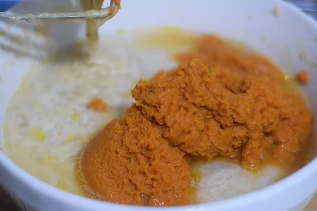 The pumpkin being added to the pumpkin bread batter. 