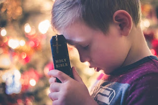 Un bimbo prega con la Bibbia tra le mani