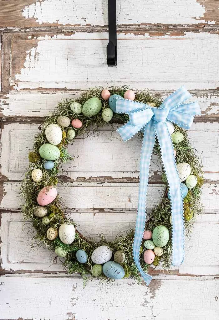 speckled eggs and moss wreath hanging on chippy white door