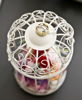 Floral confetti in a white birdcage against a grey background
