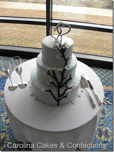 Light blue round wedding cake with white cherry blossoms decorating the