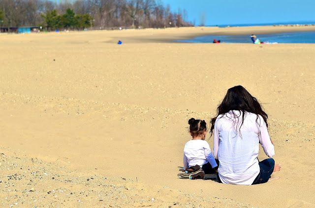 A mother and daughter read together on Orchard Beach in the Bronx.