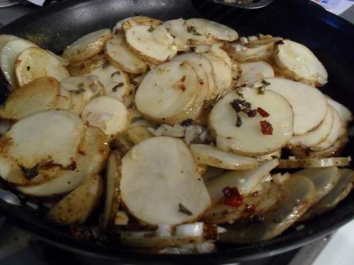 Pan filled with sliced potatoes, onions, and bell peppers