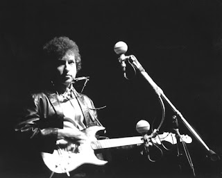 Bob Dylan playing electric guitar at Newport Festival 1965