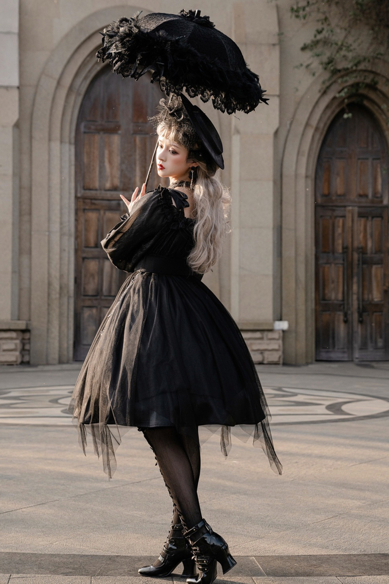 young woman in gothic lolita fasion outfit is posing in the middle of a street