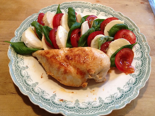 Chicken breast and slices of cheese, tomato, and basil