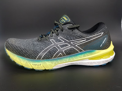Asics GT-2000 10, lateral view. A black upper with a mixed yellow and white midsole with a streak of a turquise at the top.