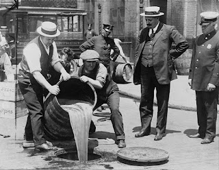 Police Commissioner John A. Leach, right, watching agents pour liquor into sewer following a raid during the height of prohibition