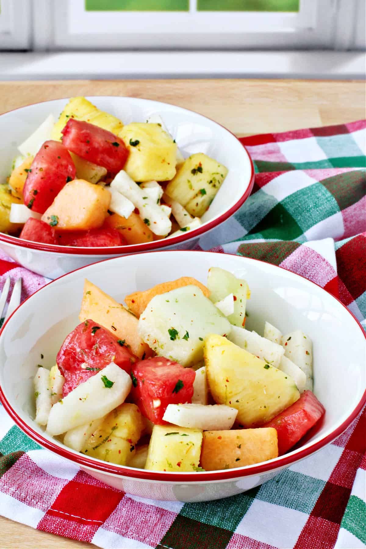 Melon, Jicama, and Pineapple Salad in red rimmed bowls.