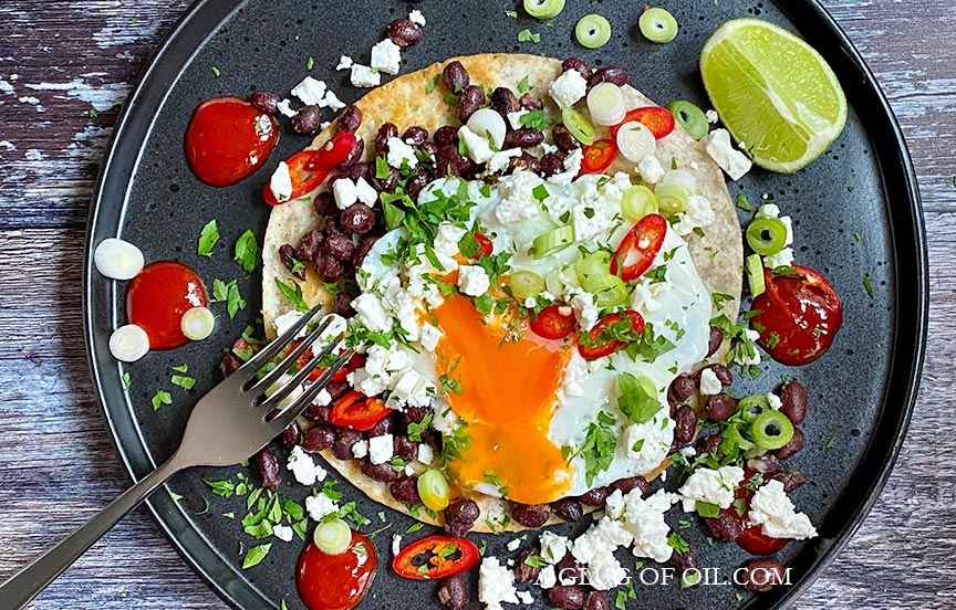 Huevos rancheros pictured on a black plate.