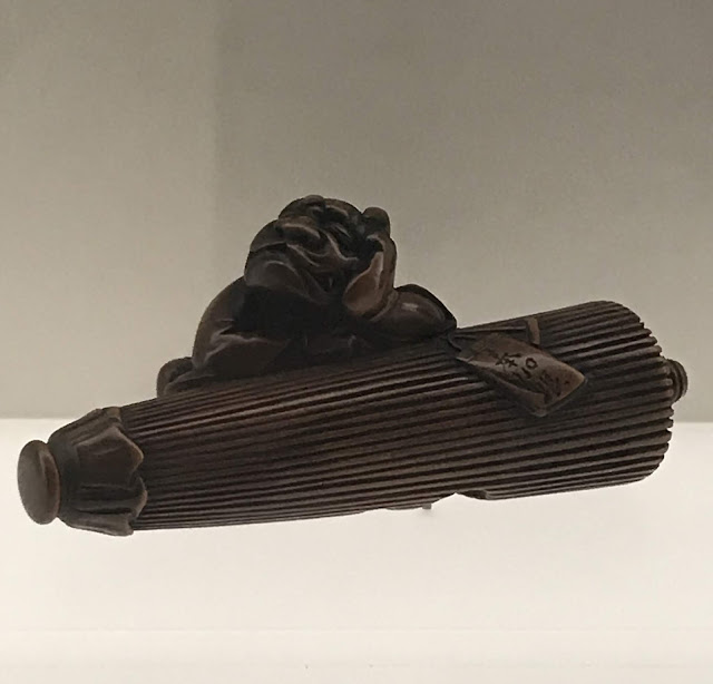 Photo of Ryukei wooden netsuke of a demon sleeping on an umbrella