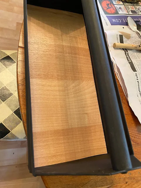 Photo of a black toolbox with wood-look vinyl bottom.