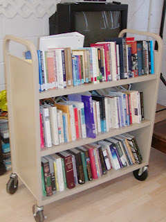 Books shelved on three-level wheeled cart