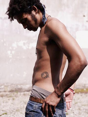 A dolphin making a circle tattoo on young Latino male's hip.