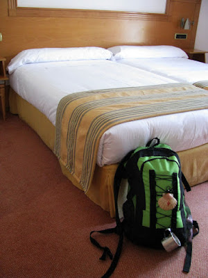 uma mochila de peregrino de Santiago encostada numa cama de hotel