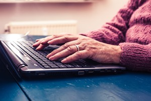 Old woman working on laptop computer at home