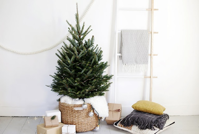 minimal neutral Scandinavian Christmas tree with fresh cut tree in woven basket with fur lining, white wood bead garland, and dipped ladder for cozy blanket throws