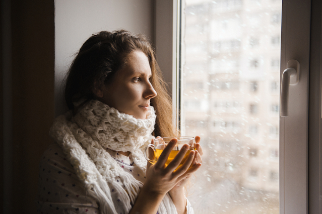 woman with a cup of tea sitting by the window.