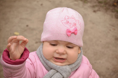 маленькая девочка в розовой шапке рассказывает что-то