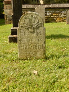 Gravestone with rounded top, stylized carving of flowers, and Gothic German script