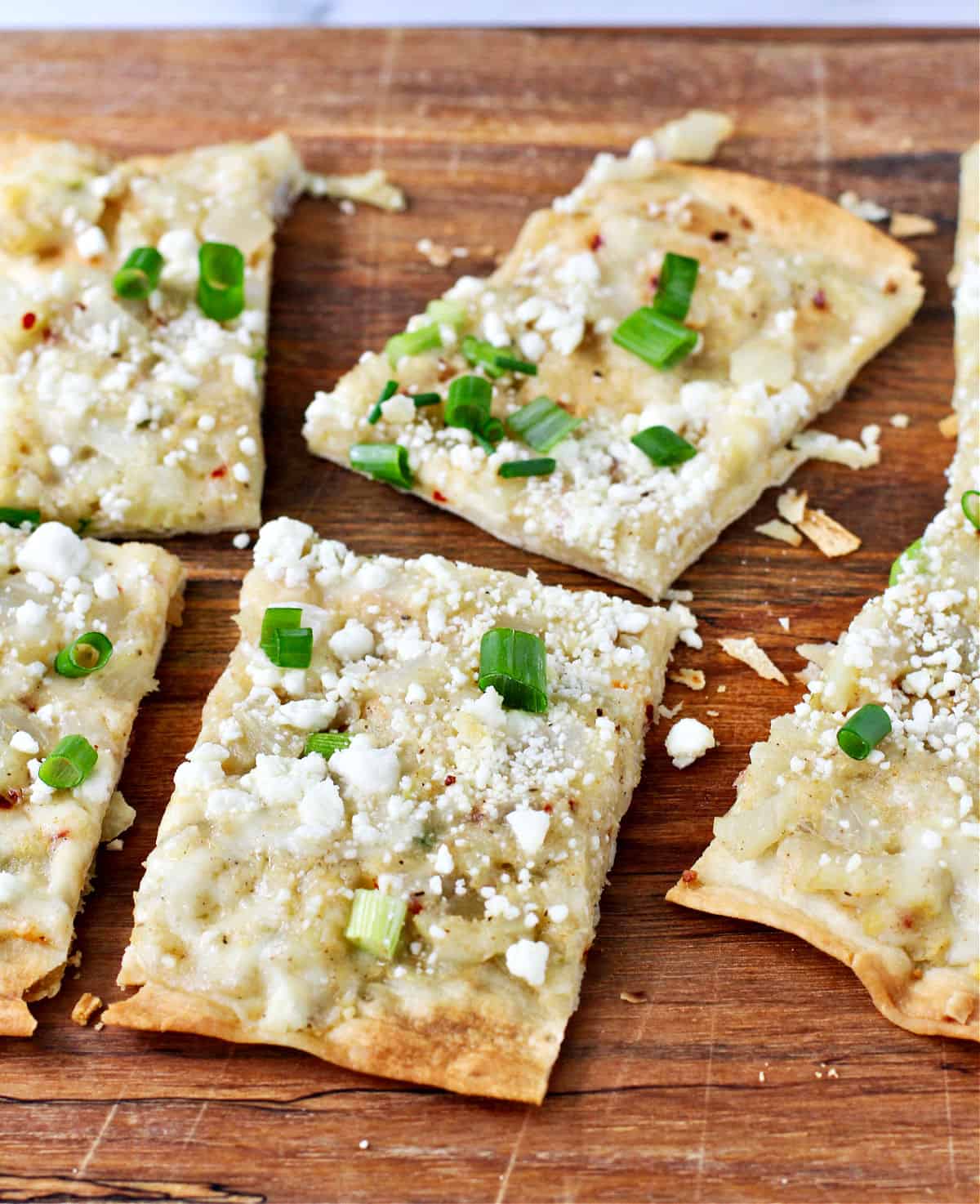 Lavash Pizza with Cauliflower, Fennel, and Mozzarella cut into pieces on a cutting board.