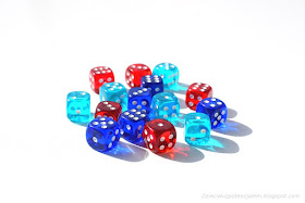 na zdjęciu piętnaście kostek w kolorach czerwonym, błękitnym i niebieskim leżących a środku stołu