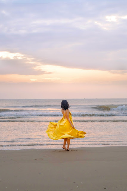 Mujer con vestido amarillo en la orilla de la playa
