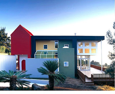 A multi-colored modern house with navy blue, green, yellow and red blocks of color on exterior of house