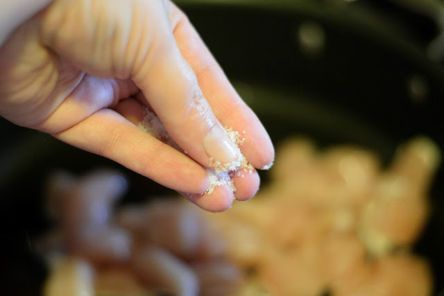 Salt being added to the chicken in the skillet.