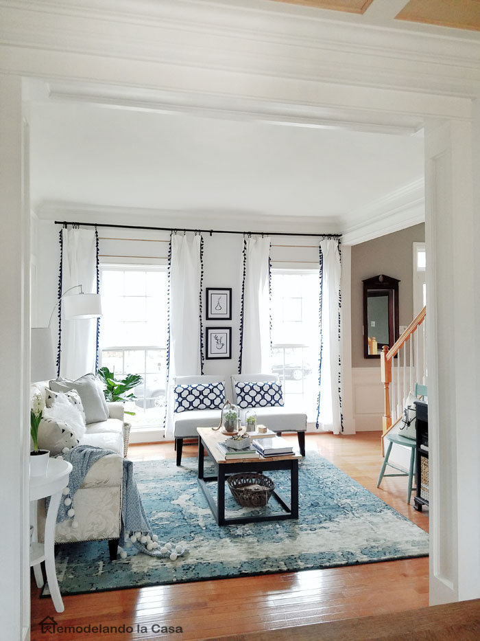 living room with blue rug and white curtains and industrial coffee table