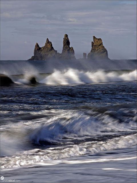 White waves of the Atlantic Ocean with black lava columns of the Reynisdrangar coming out of the sea, Iceland