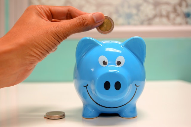 Person putting money in a blue piggy bank