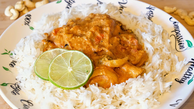 Butter curry on a plate with white rice and slices of lime