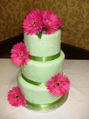 An assortment of green or green and white wedding cakes with pink flowers