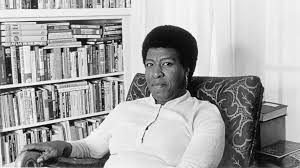 Black and white photograph of Octavia Butler seated in front of a bookcase
